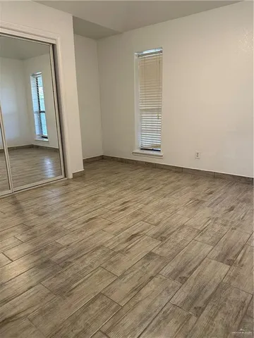an empty room with wooden floor and mirror