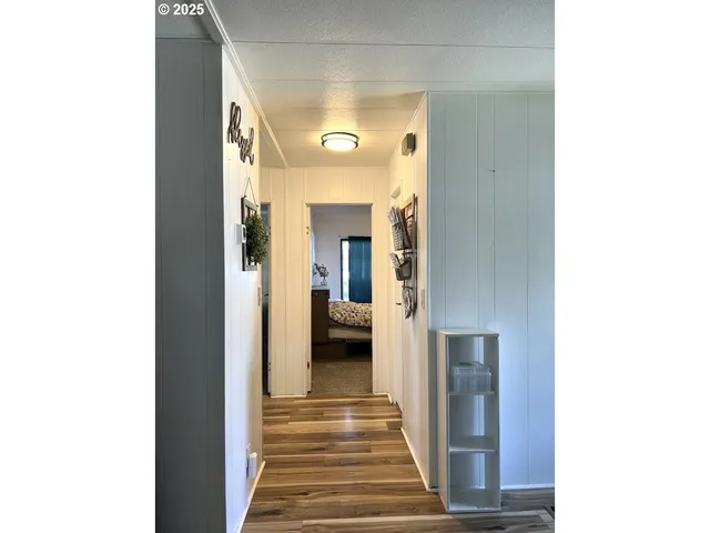 a view of a hallway with wooden floor and a large mirror
