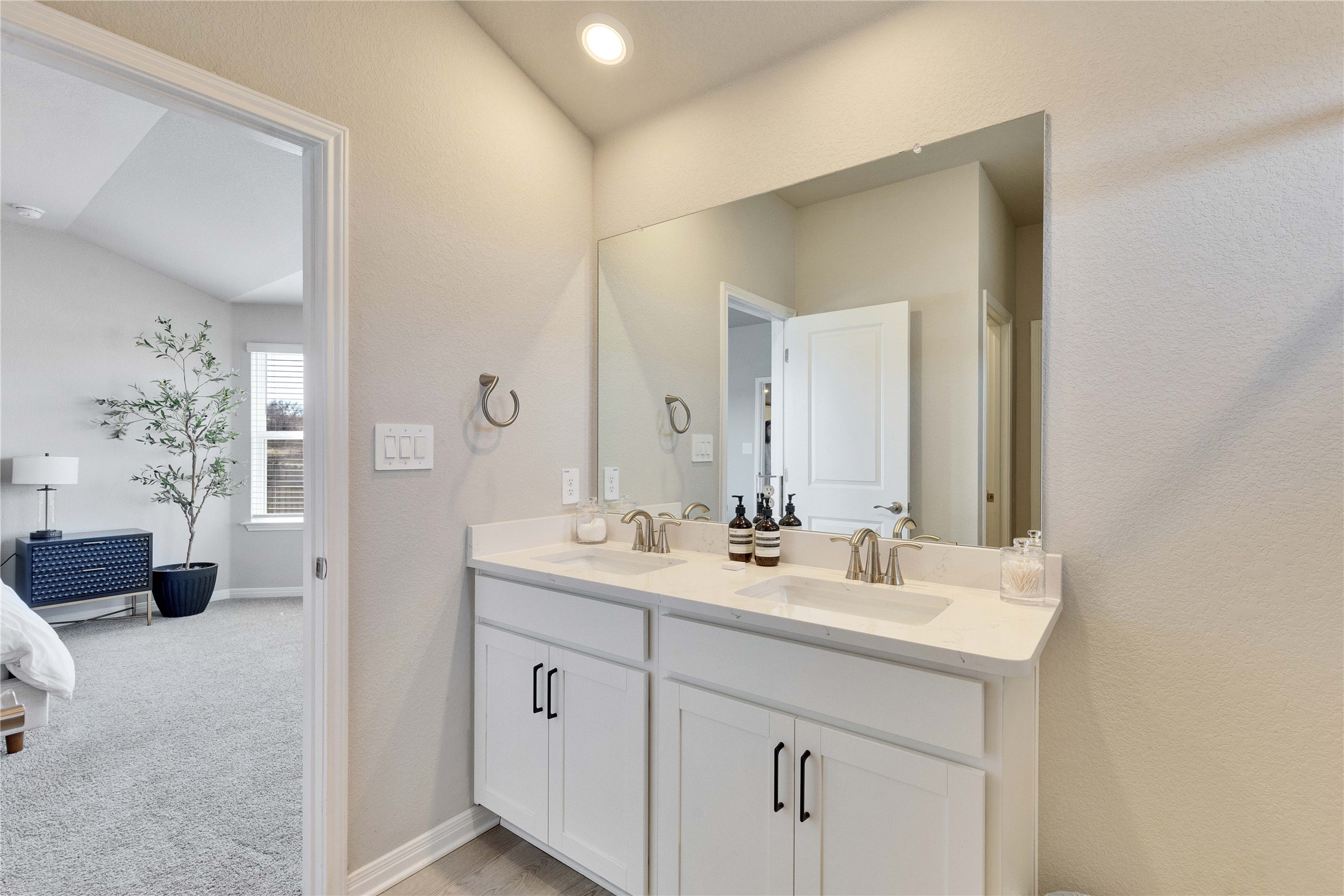 12308 Dairywork Road Buda, TX 78610 - Photo 14 of 24 The bright primary bathroom features a spacious dual-sink vanity topped with quartz.