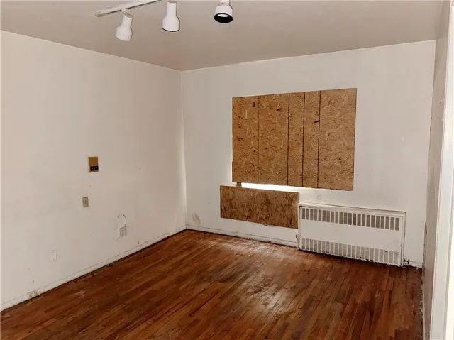 an empty room with wooden floor and a refrigerator