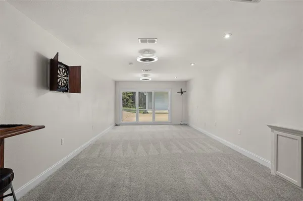an empty room with wooden floor chandelier and window