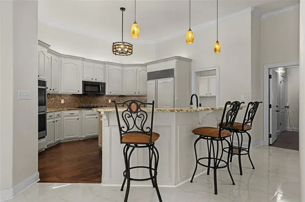 a kitchen with stainless steel appliances kitchen island granite countertop a table chairs and a refrigerator