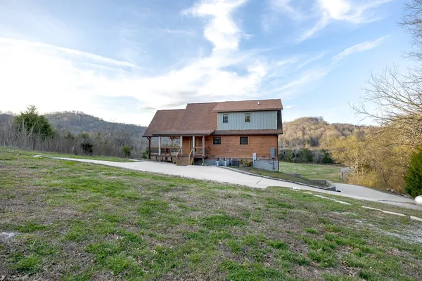 a front view of a house with yard and trees in the background