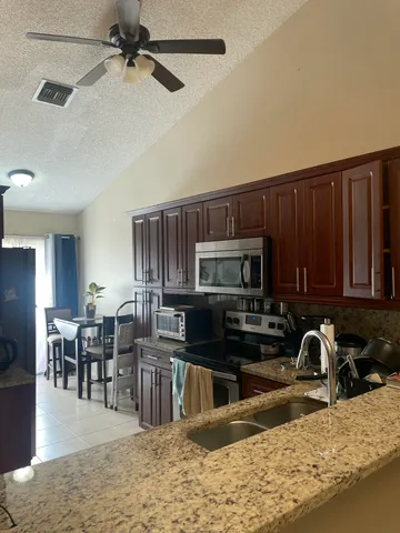 a kitchen with stainless steel appliances granite countertop a stove top oven a sink a dining table and chairs