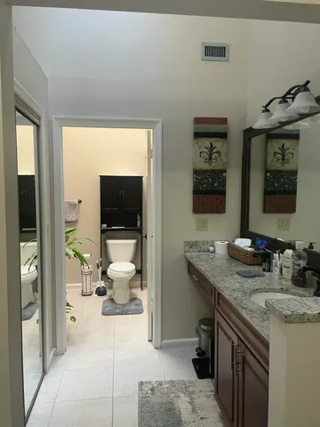 a en suite bathroom with a granite countertop sink and a large mirror