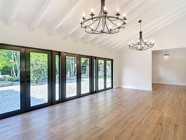 a view of a room with wooden floor chandelier and windows