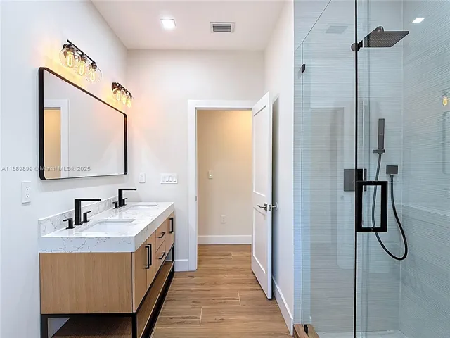 a spacious bathroom with a double vanity sink a mirror and shower
