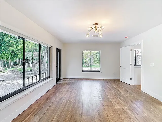 an empty room with wooden floor and windows