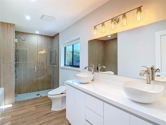 a bathroom with a double vanity sink toilet and shower