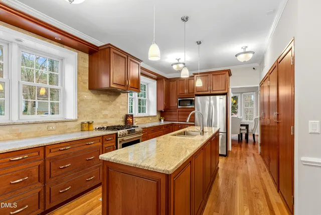 a large kitchen with kitchen island a large counter space wooden floor and stainless steel appliances
