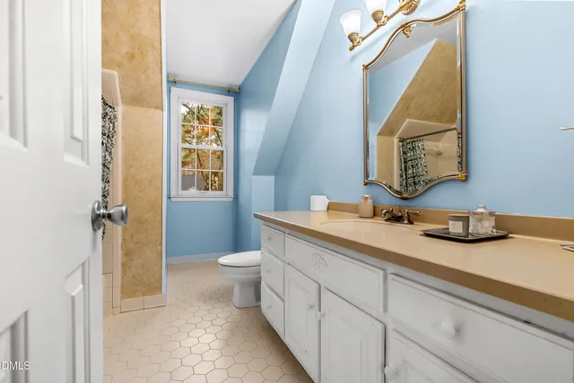 a view of a hallway with wooden floor and a bathroom