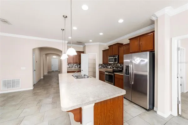 a kitchen with stainless steel appliances kitchen island granite countertop a refrigerator a oven a sink with a countertop and chairs