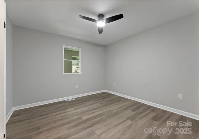 a view of a room with wooden floor and a ceiling fan