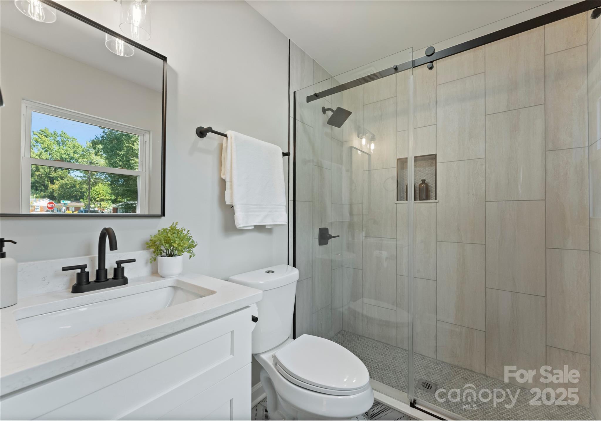 2900 Enfield Road Charlotte, NC 28205 - Photo 21 of 35 a bathroom with a sink a toilet a glass door a shower and a mirror