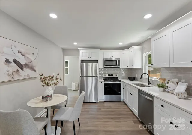 a kitchen with stainless steel appliances a dining table chairs refrigerator and cabinets