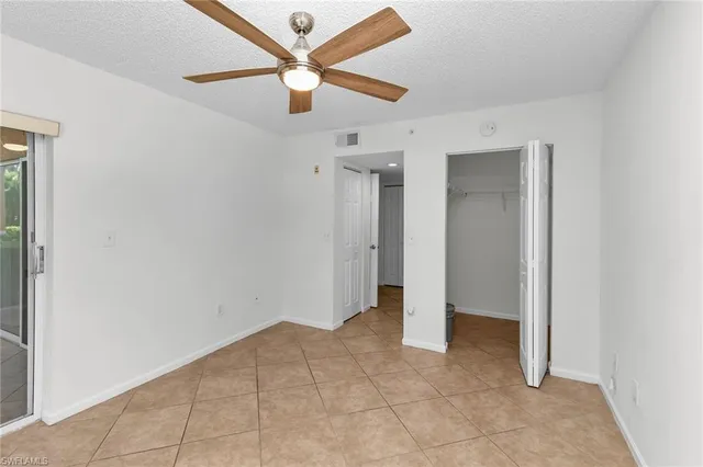 an empty room with closet and a ceiling fan