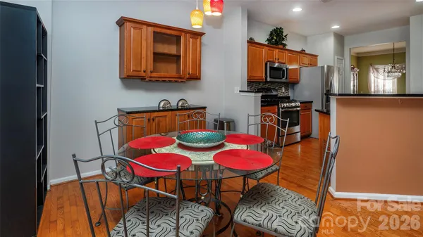a kitchen with stainless steel appliances kitchen island granite countertop a dining table chairs and a sink