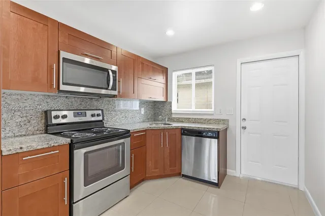 a kitchen with stainless steel appliances granite countertop white cabinets a stove a microwave and a window