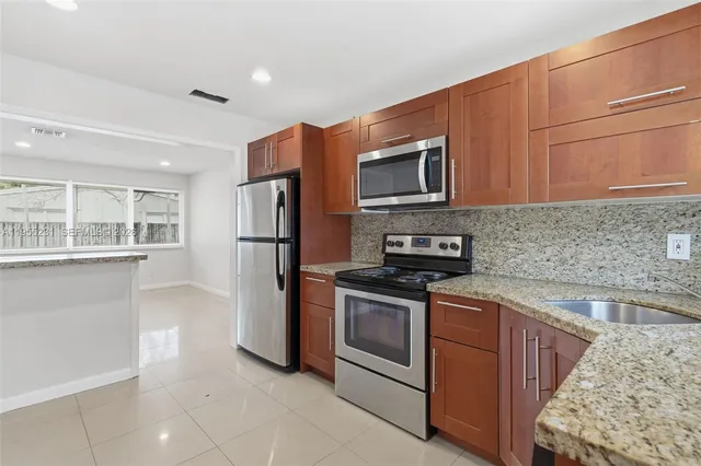 a kitchen with stainless steel appliances granite countertop a refrigerator sink and stove