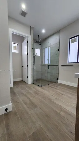 a view of a hallway with wooden floor and a bathroom