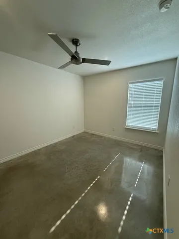 an empty room with a ceiling fan and window