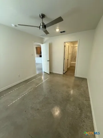 an empty room with a ceiling fan and carpet