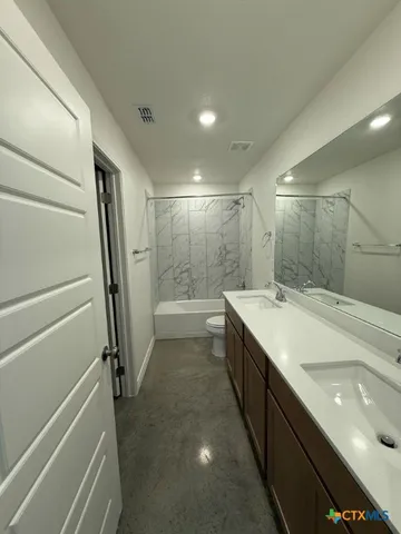a bathroom with a double vanity sink and mirror with bathtub