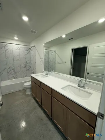 a spacious bathroom with a double vanity sink large mirror and a bathtub