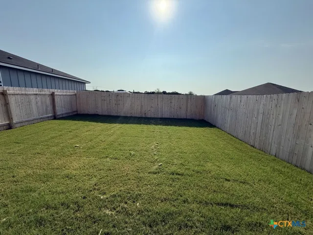 a view of a backyard with potted plants and wooden fence