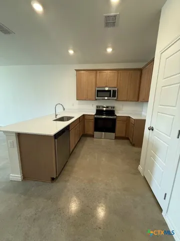 a large kitchen with stainless steel appliances granite countertop a sink and cabinets