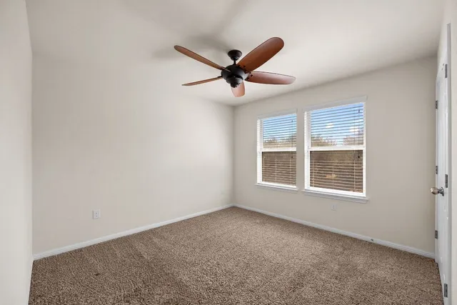 an empty room with a window and a ceiling fan