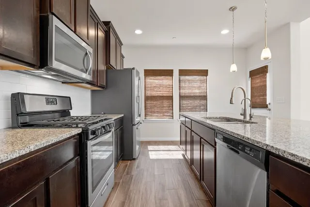 a kitchen with stainless steel appliances granite countertop a stove a sink and a microwave
