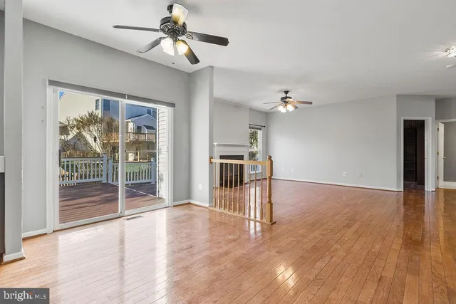 a view of a livingroom with wooden floor a ceiling fan and windows