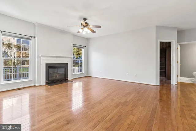 a view of an empty room with wooden floor fireplace and a window