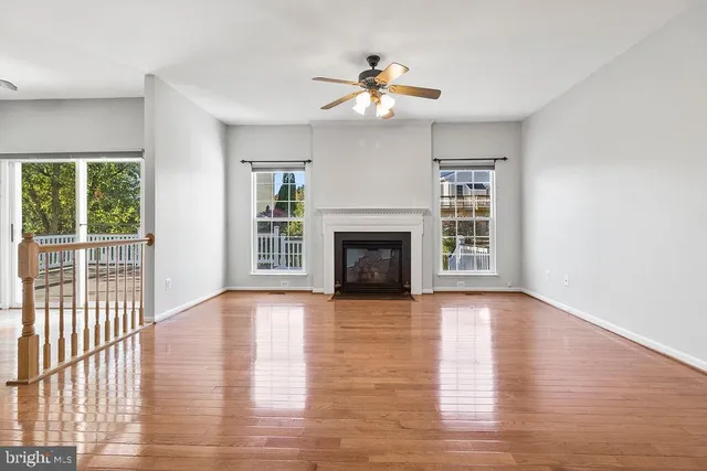 a view of an empty room with wooden floor fireplace and a window