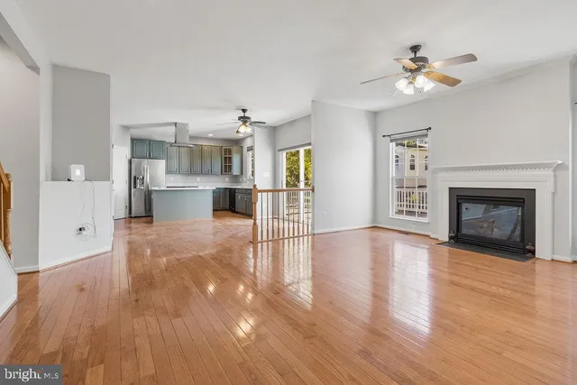 a view of a livingroom with wooden floor a ceiling fan and staircase