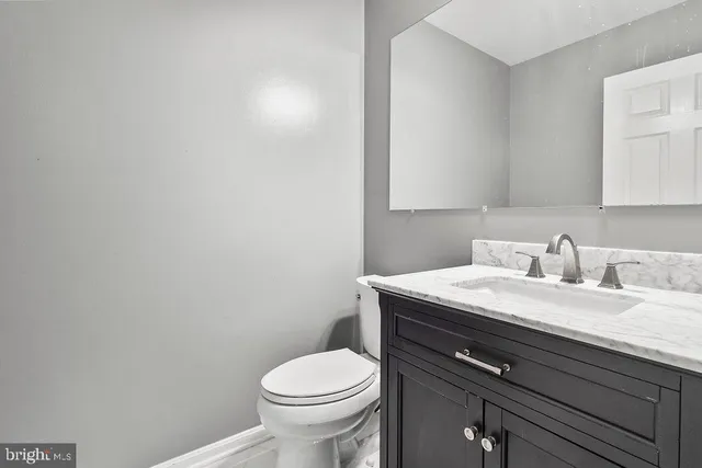a bathroom with a granite countertop toilet sink and mirror