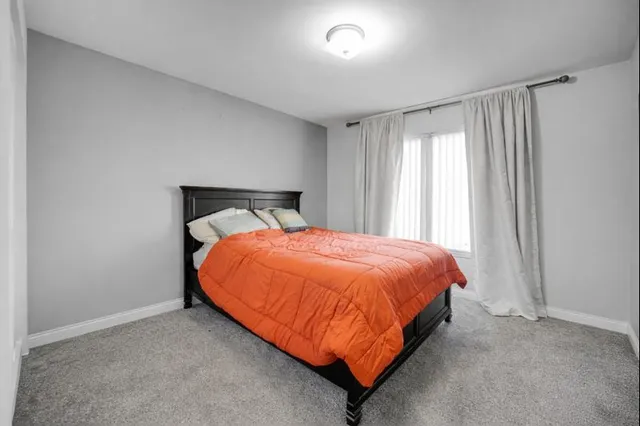 a bed sitting in a spacious bedroom next to a window and a bathroom