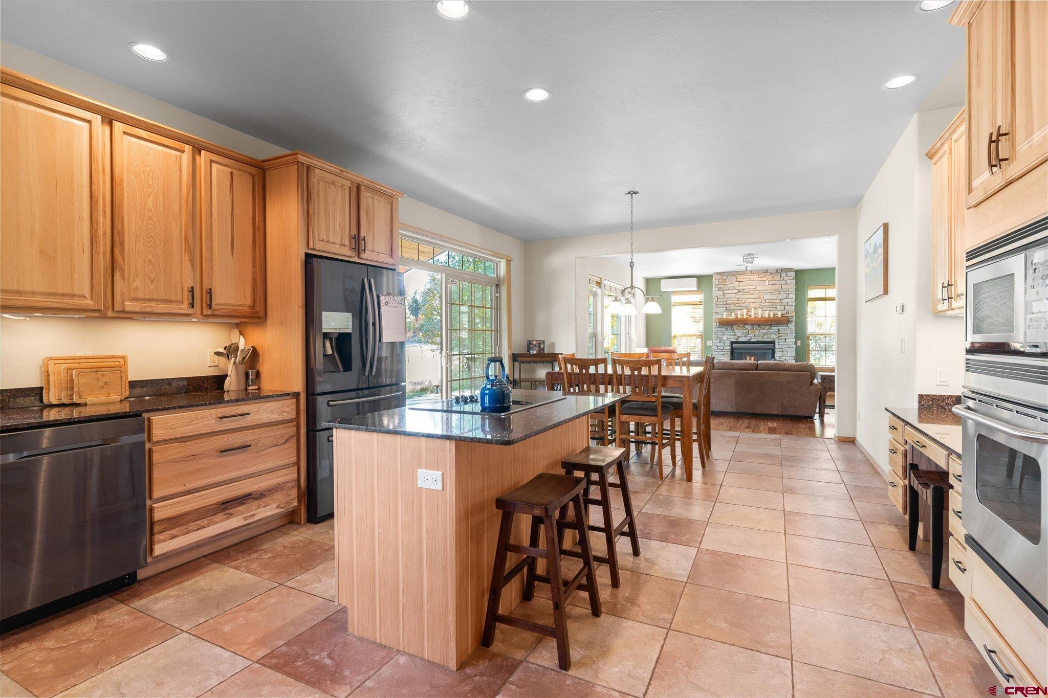 73 Ute Pass Road Durango, CO 81301 - Photo 13 of 44 a kitchen with stainless steel appliances kitchen island granite countertop a stove top oven a sink a dining table and chairs with wooden floor