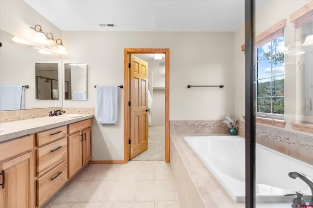 a spacious bathroom with a tub sink and mirror