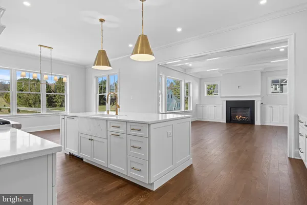 a kitchen with stainless steel appliances granite countertop a stove a sink a center island and a wooden floor