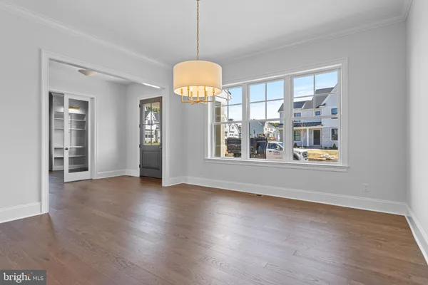 a view of an empty room with wooden floor and windows