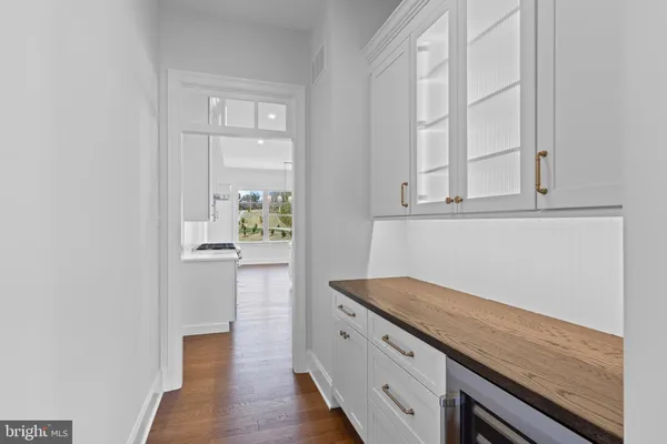 a hallway with white cabinets and wooden floor