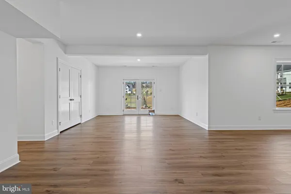 a view of an empty room with window and wooden floor