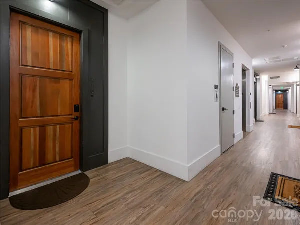 a view of a hallway with wooden floor and closet