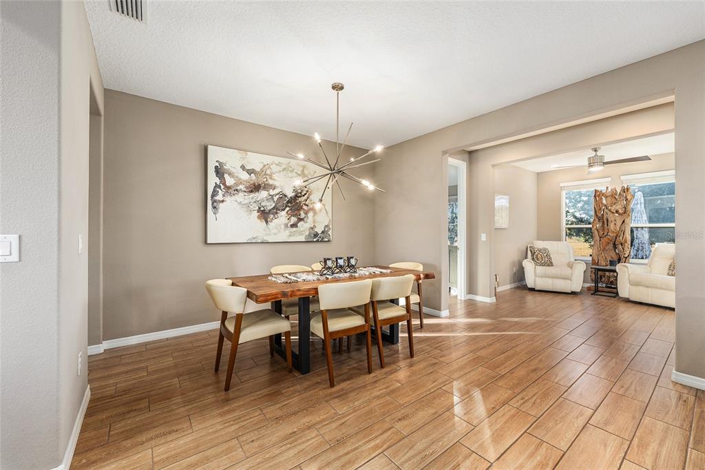 5589 Northwest 40th Loop Ocala, FL 34482 - Photo 13 of 47 a dining room with wooden floor a chandelier a wooden table and chairs