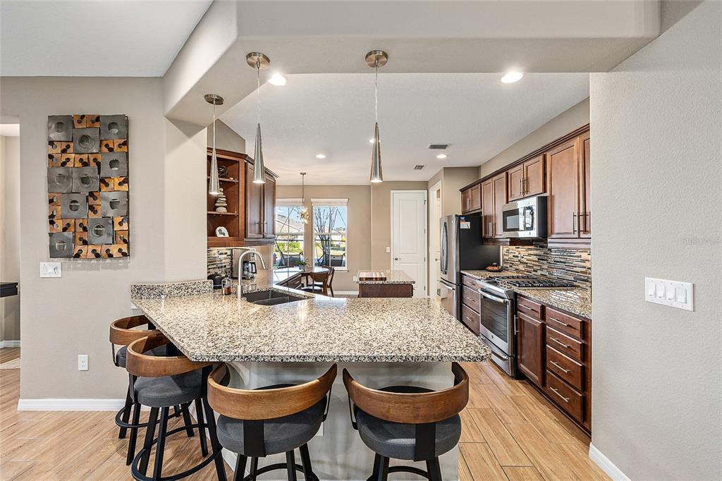 5589 Northwest 40th Loop Ocala, FL 34482 - Photo 16 of 47 a kitchen with granite countertop kitchen island stainless steel appliances a dining table and chairs