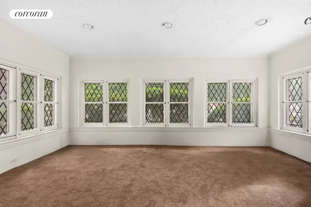 an empty room with windows and fireplace
