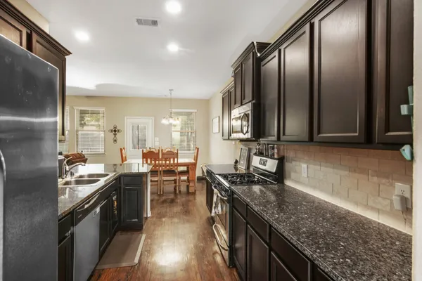a kitchen with stainless steel appliances granite countertop a stove top oven a sink and dishwasher