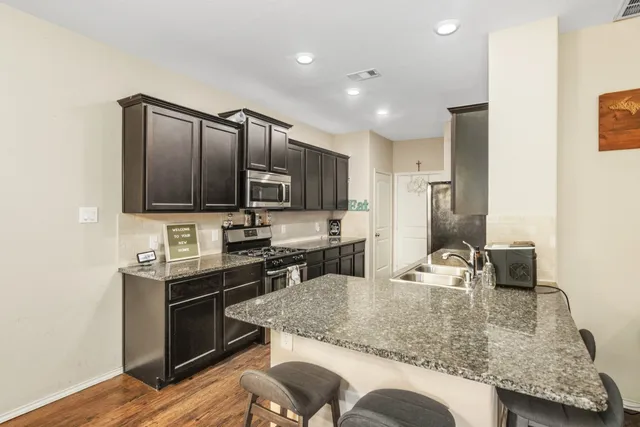 a kitchen with stainless steel appliances granite countertop a sink refrigerator and microwave